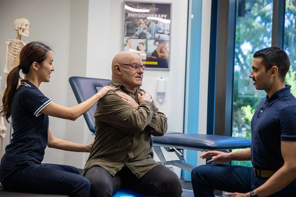 Flinders Physio students work with an educator wearing a realistic silicone mask to aid real-life role play as a patient. 